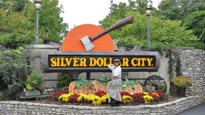 A sign for Silver Dollar City with a large axe and a wooden wagon wheel.