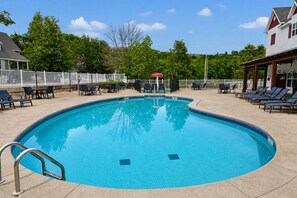A swimming pool with lounge chairs and a covered area.