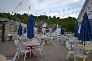 Outdoor seating with tables and chairs, string lights, and a building with a sign in the background. - Huge 4BDR/3BA cottage  in Stormy Point Village with fireplace and rec room! (Branson)