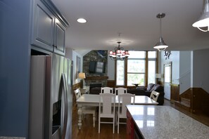 A modern kitchen with a dining area, granite countertops, and a stone fireplace. - Huge 4BDR/3BA cottage  in Stormy Point Village with fireplace and rec room! (Branson)