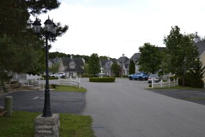 A residential street with houses, a white picket fence, and parked cars. - Huge 4BDR/3BA cottage  in Stormy Point Village with fireplace and rec room! (Branson)