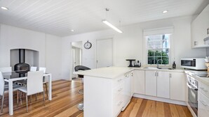 Una cucina moderna con mobili bianchi, forno integrato, microonde e zona pranzo con tavolo e sedie.
