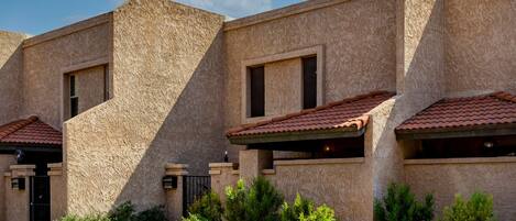 A building with a stucco exterior, multiple windows, and a tiled roof.