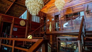Un interior de madera con una escalera, candelabros y un ambiente rústico.