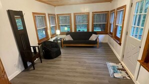 Une pièce avec un plafond en bois, un lit, un bureau, une chaise et une fenêtre avec des stores.
