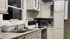 Une cuisine moderne avec des meubles blancs, un plan de travail en granit, des appareils électroménagers en acier inoxydable et une fenêtre offrant une belle vue.