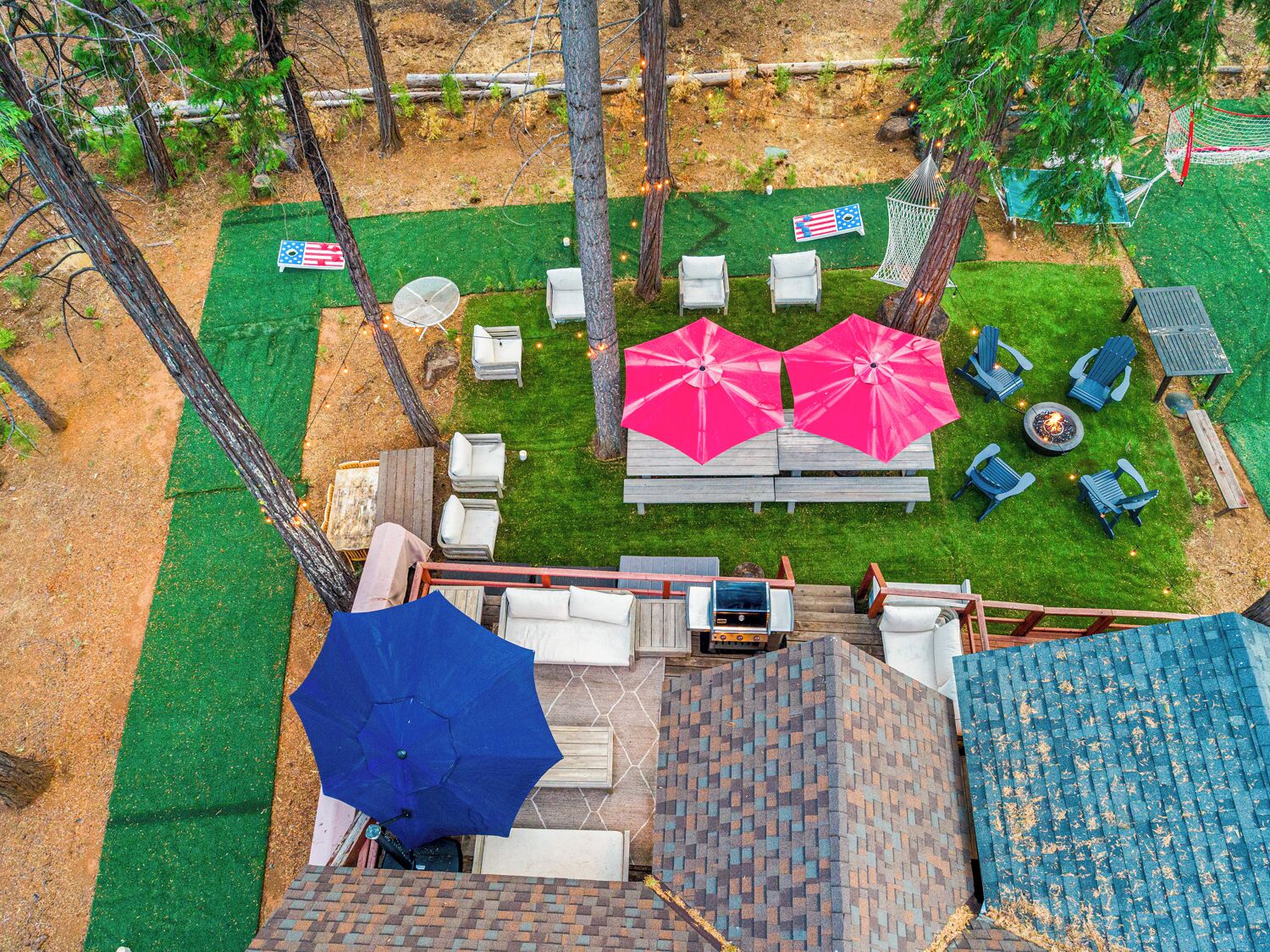 A backyard with a fire pit, outdoor seating, and a hammock.