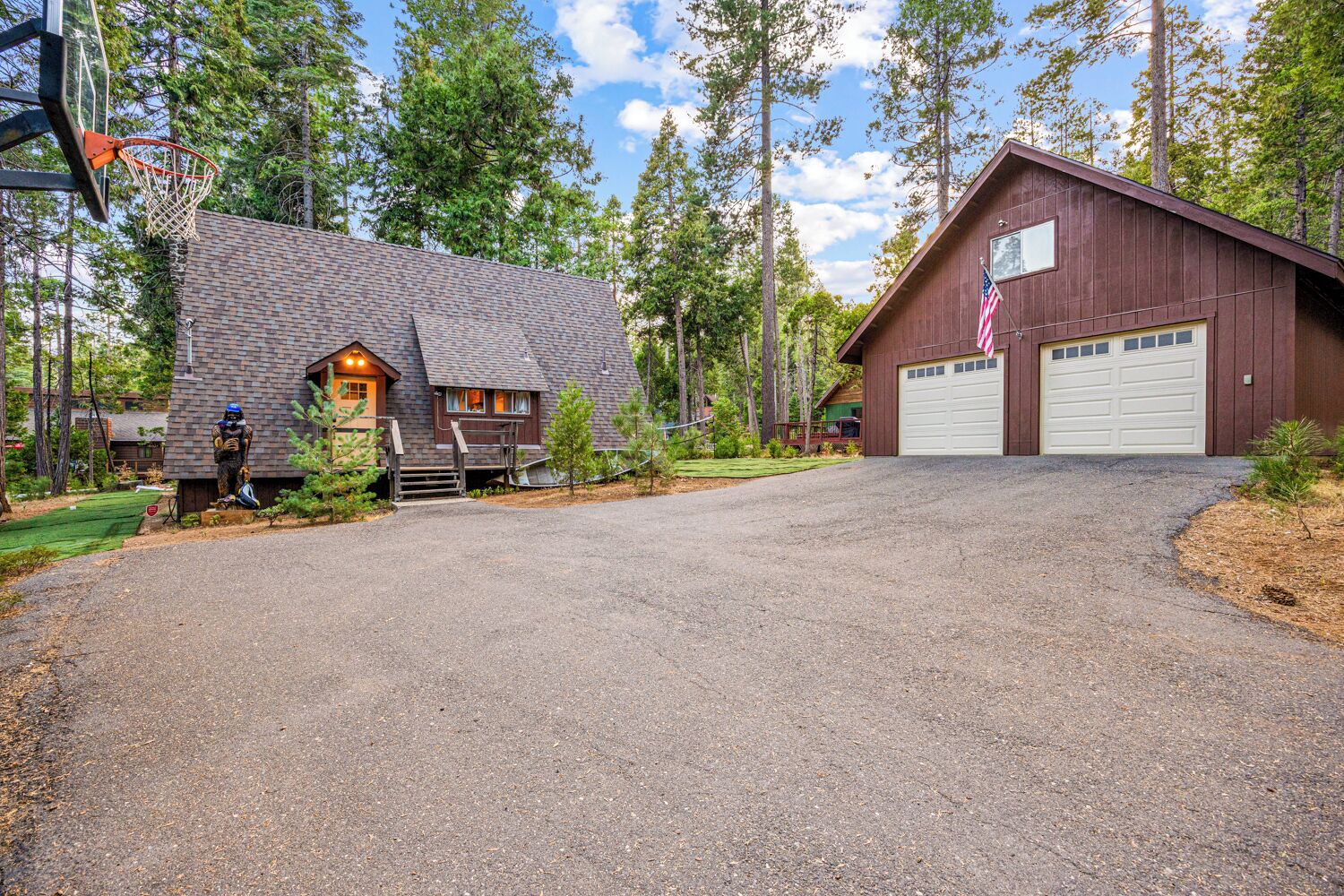 A two-story house with a garage, surrounded by trees.