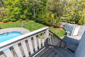 Enjoy a serene backyard retreat with a swimming pool and deck surrounded by lush trees and shrubs.