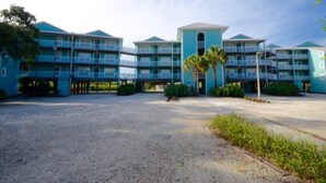 A multi-story hotel with a central entrance, balconies, and a parking area. - Nature's Landing - A102 Budget Rates Downtown Unit (Cedar Key)