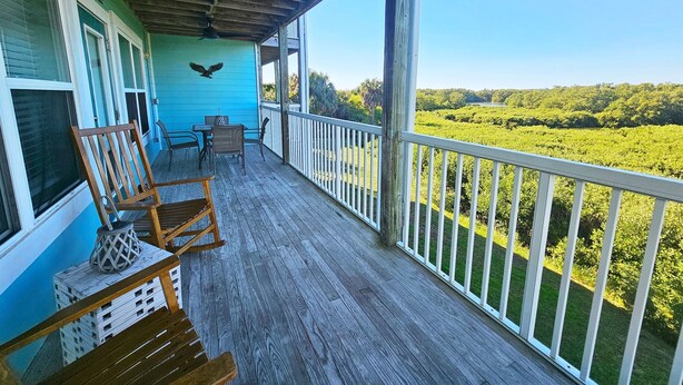 A wooden deck with a view of a green landscape. - Nature's Landing A104 Prettiest Condo in Town! (Cedar Key)