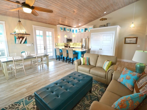 A spacious living room with a sofa, ottoman, and dining area with chairs and a table.