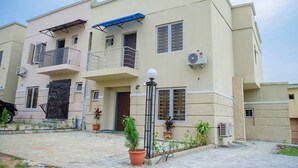 Um edifício residencial com vários andares, varandas, aparelhos de ar condicionado e plantas em vasos.