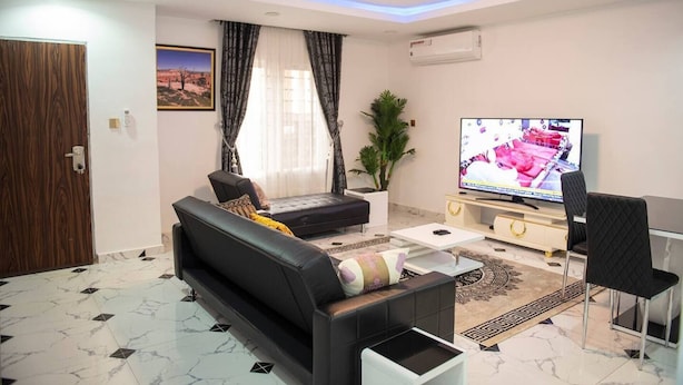 Uma sala de estar moderna com um sofá, uma mesa de centro, uma televisão e uma planta.