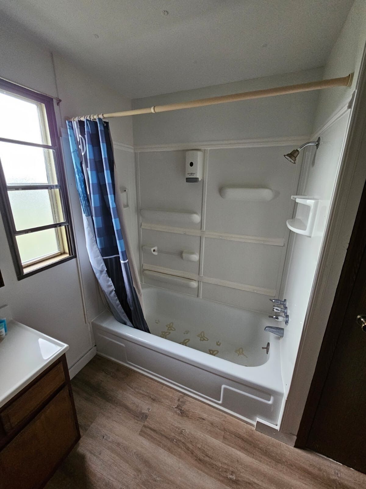A bathroom with a bathtub, shower, and a window with a curtain.