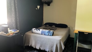 Une chambre d’hôtel avec un lit, un bureau doté d’une lampe et un téléviseur fixé au mur.