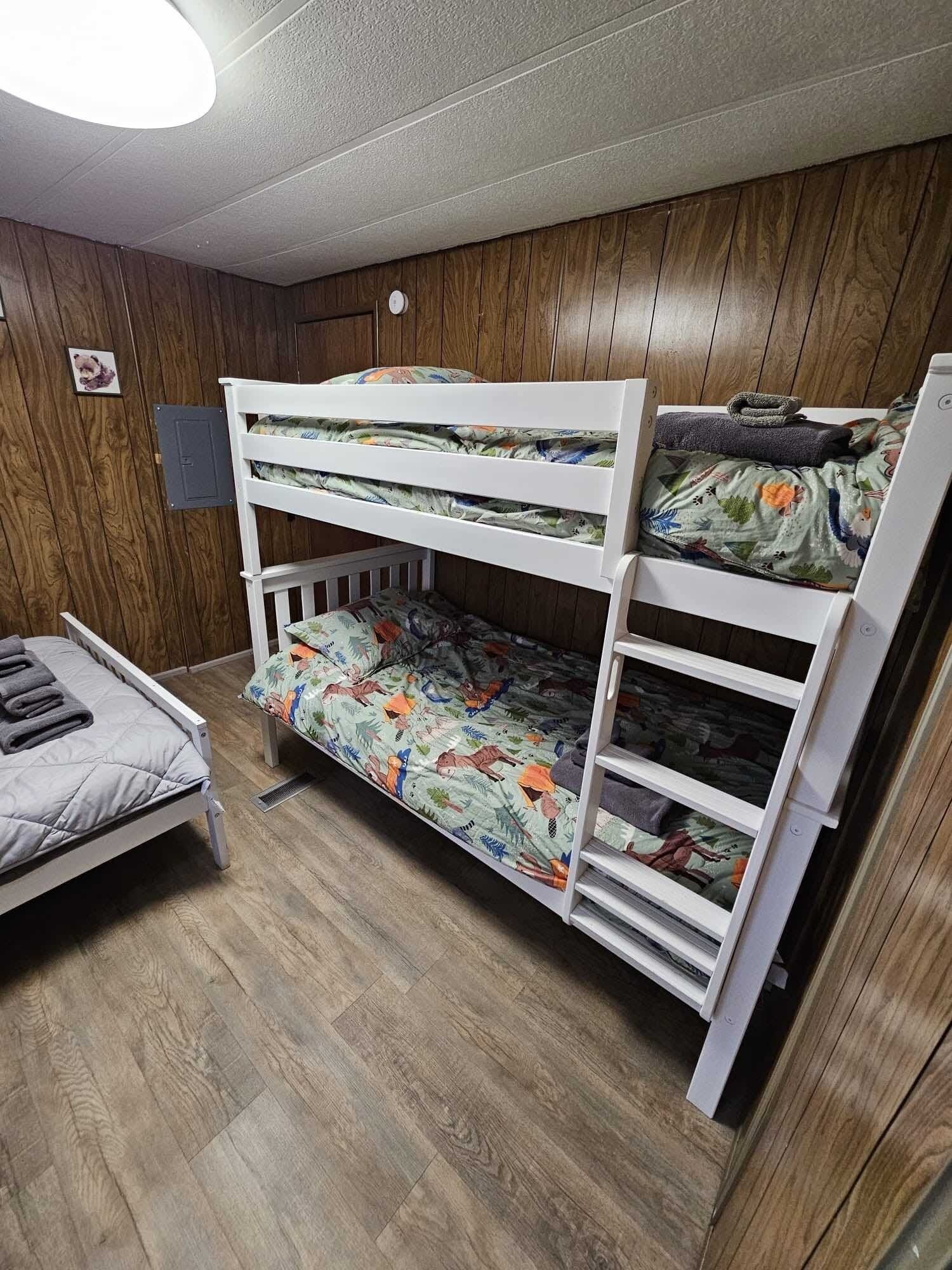 A bunk bed with a lower bunk and a single bed with a grey quilt.