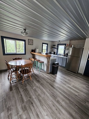 A kitchen with a dining area, wooden flooring, and a view of the outdoors. - Denali RV Park and Motel (Healy)