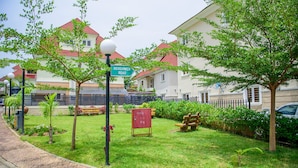 A residential area with houses, a street sign for Mekunwen Road, a lamp post, and a small garden with benches and a tree. - Lovely One-bed Apartment Located in Abuja (Abuja)