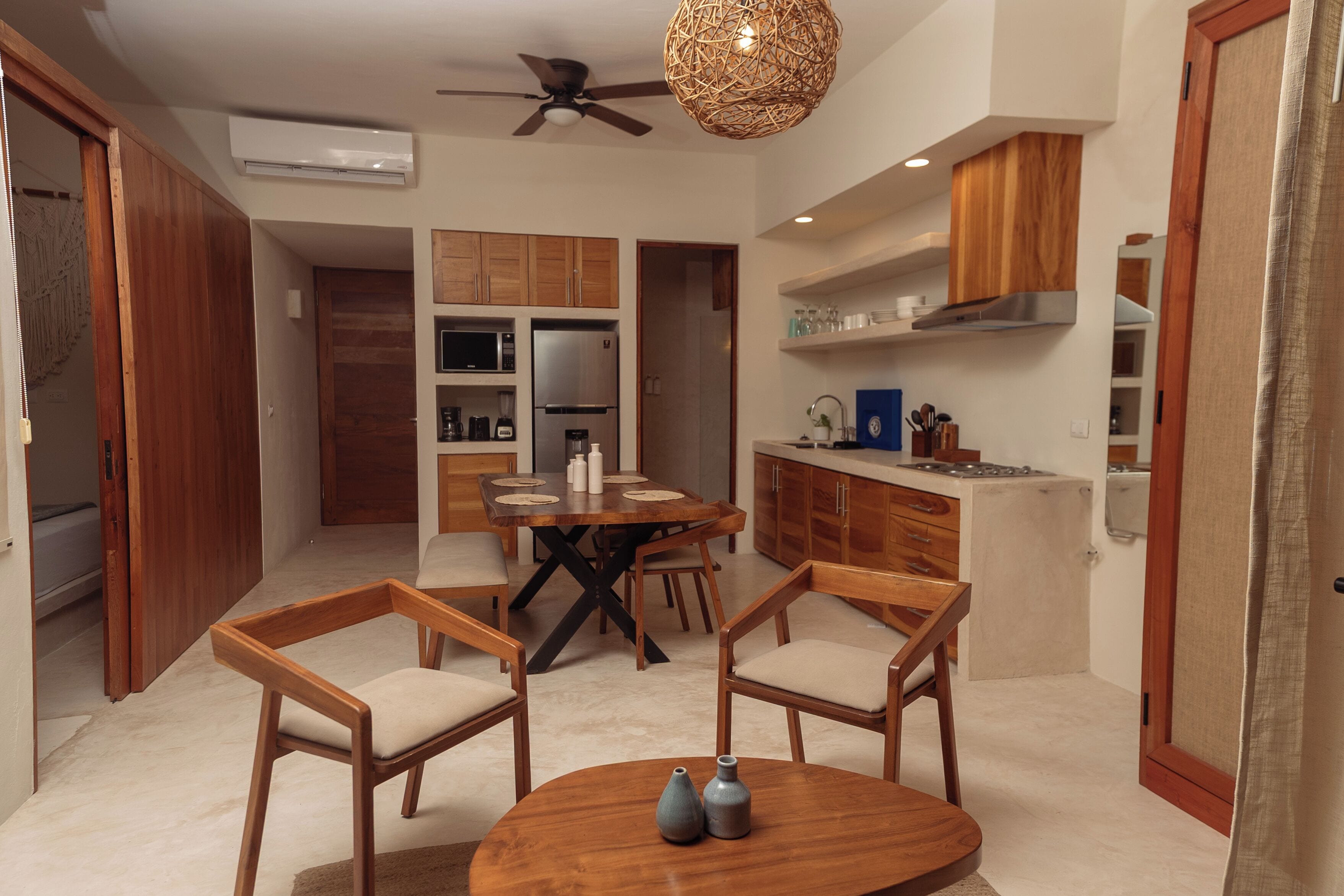 Una cocina moderna con armarios de madera, un comedor con una mesa redonda y sillas, y un ventilador de techo.