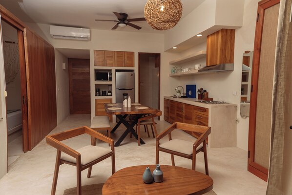 A modern kitchen with wooden cabinets, a dining area with a round table and chairs, and a ceiling fan.