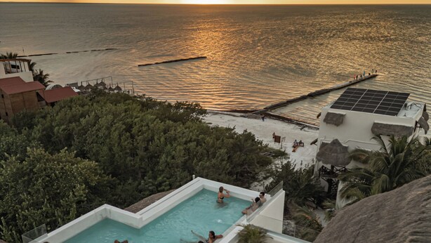 A swimming pool with a view of the sea at sunset. - Casa Astral Hotel Boutique and Apartments (Isla Holbox)
