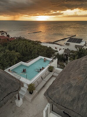 A swimming pool with a view of the sea at sunset. - Casa Astral Hotel Boutique and Apartments (Isla Holbox)