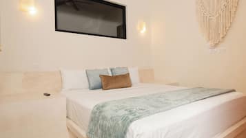 A bedroom with a bed, a wall-mounted TV, and a macrame wall hanging.