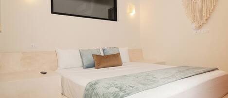 Une chambre avec un lit, un téléviseur fixé au mur et une décoration murale en macramé.