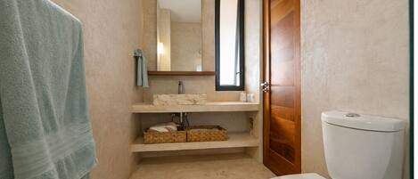 A bathroom with a toilet, a sink, a mirror, and a towel rack.