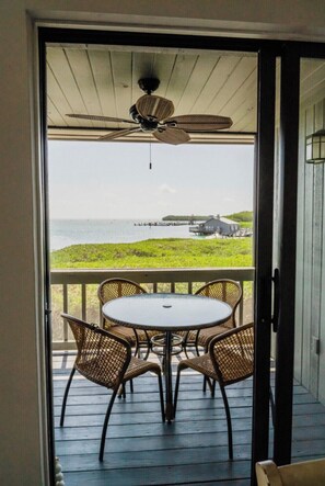 Enjoy the ocean view from this room, featuring a ceiling fan, table, and chairs, with access to the outdoors.