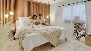 A modern bedroom with a large bed, a wooden slat wall, and a view of the outdoors.