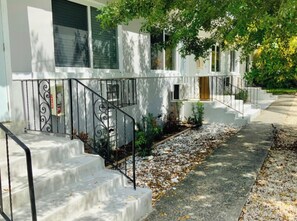 A residential building with a white exterior, a front porch, and a staircase leading to the entrance. - Cute and Cozy Studio Apt in the Heart of Miami!#3 (Miami)