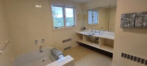 Un baño con bañera, lavamanos y un espejo grande.