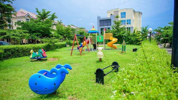 Ein Spielplatz mit verschiedenen Spielgeräten, darunter Schaukeln, Rutschen und einer blauen Kletterkonstruktion.