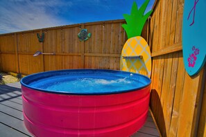 A small inflatable pool with a pineapple decoration on the side, a wooden fence, and a blue sky.