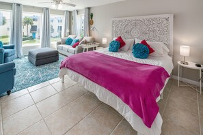 A hotel room with a large bed, a desk, a chair, and a view of the outside.