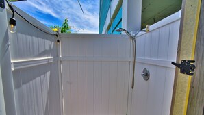 A white wooden outdoor shower enclosure with a wooden floor, a showerhead, and a faucet. - Comfy King beds, close to beach, pool + pet friendly  (Eastpoint)