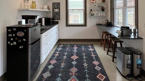 Una cocina compacta con refrigerador, microondas y cafetera. Hay dos contenedores de basura y una ventana con vista a una terraza.