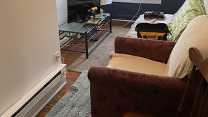 A cozy living room with a television, lamp, and a window with blinds. - Apt near Temple, St. Christ, Jean, Abington  (Philadelphia)