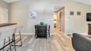 Una sala moderna con comedor, televisor y pasillo que conduce a otra habitación.