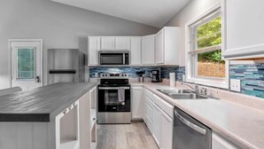 Una cocina moderna con armarios blancos, electrodomésticos de acero inoxidable y encimera de madera.