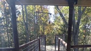 Un puente de madera con barandillas de metal, rodeado de árboles y follaje.