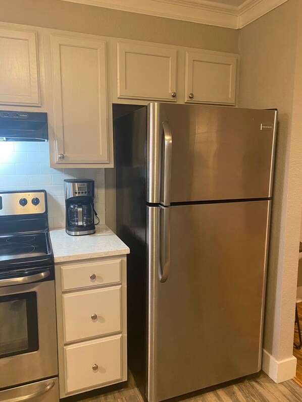 A kitchen with a stainless steel refrigerator, a coffee maker, and a stove.