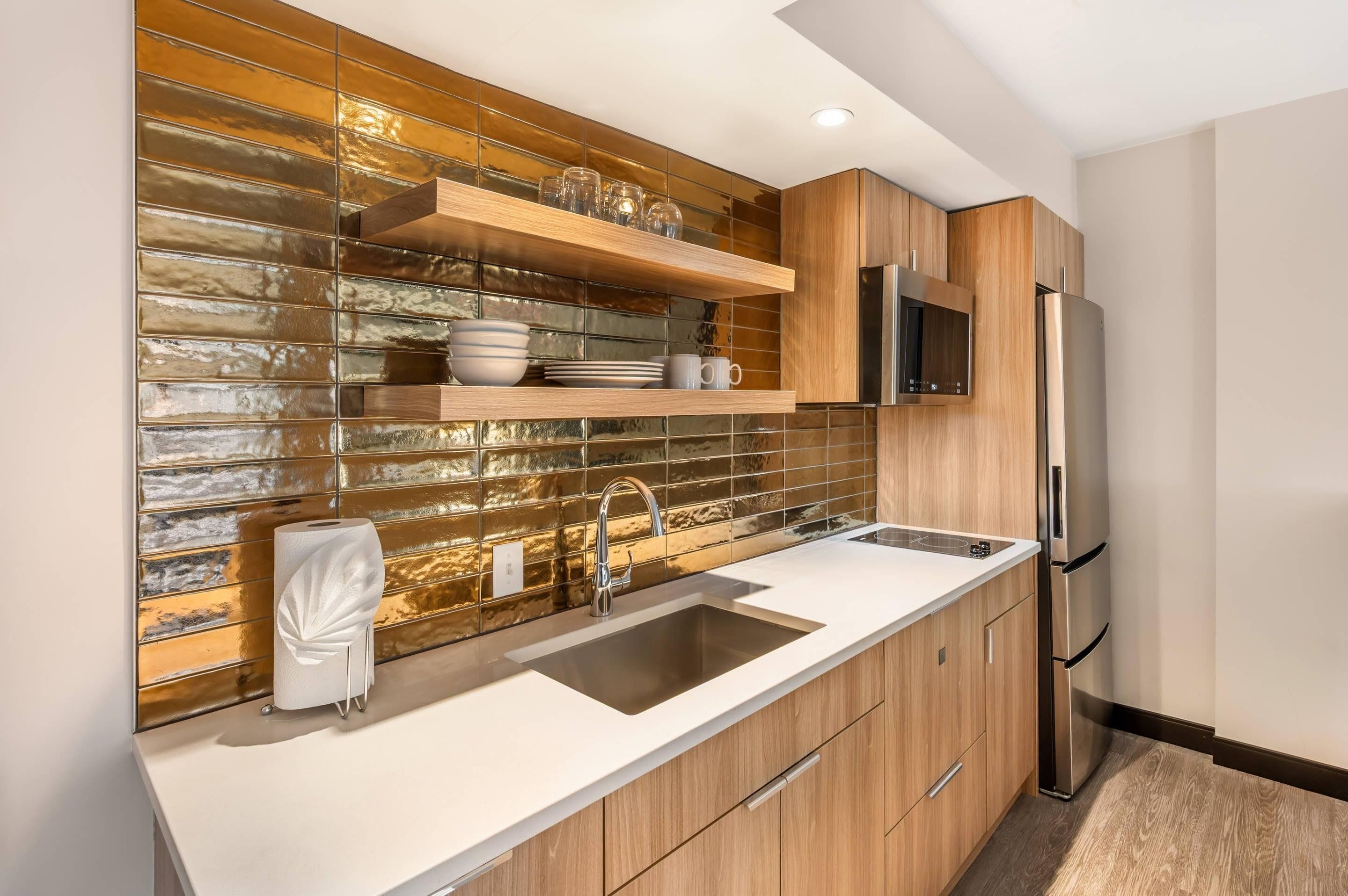 Una cocina moderna con refrigerador de acero inoxidable, armarios de madera, pileta doble y un salpicadero decorativo.