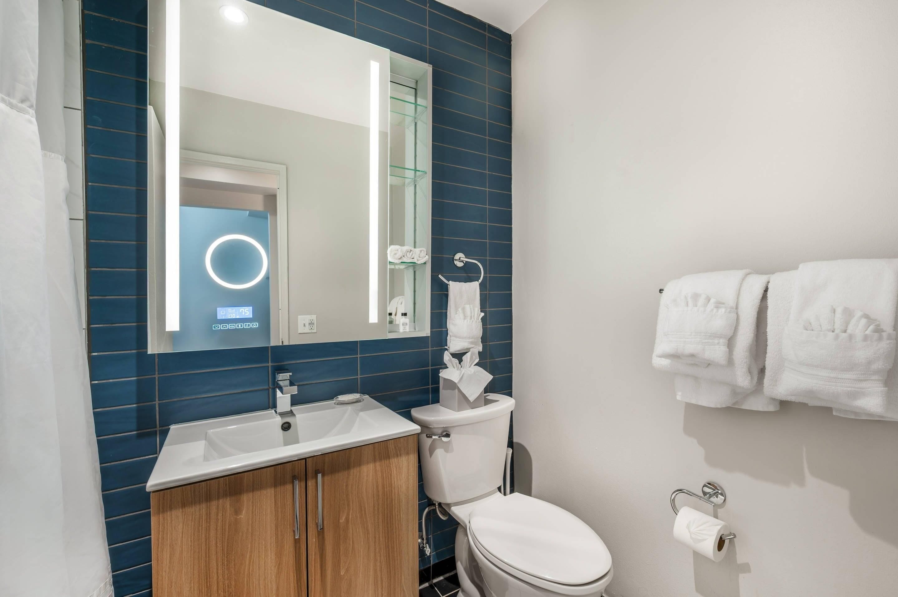 Une salle de bain avec un lavabo blanc, des toilettes, un miroir et un porte-serviettes.