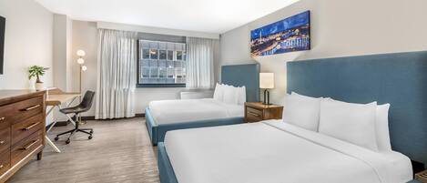 Habitación de hotel con dos camas, un escritorio, una silla, un aparador, una lámpara, un cuadro y una ventana con cortinas.