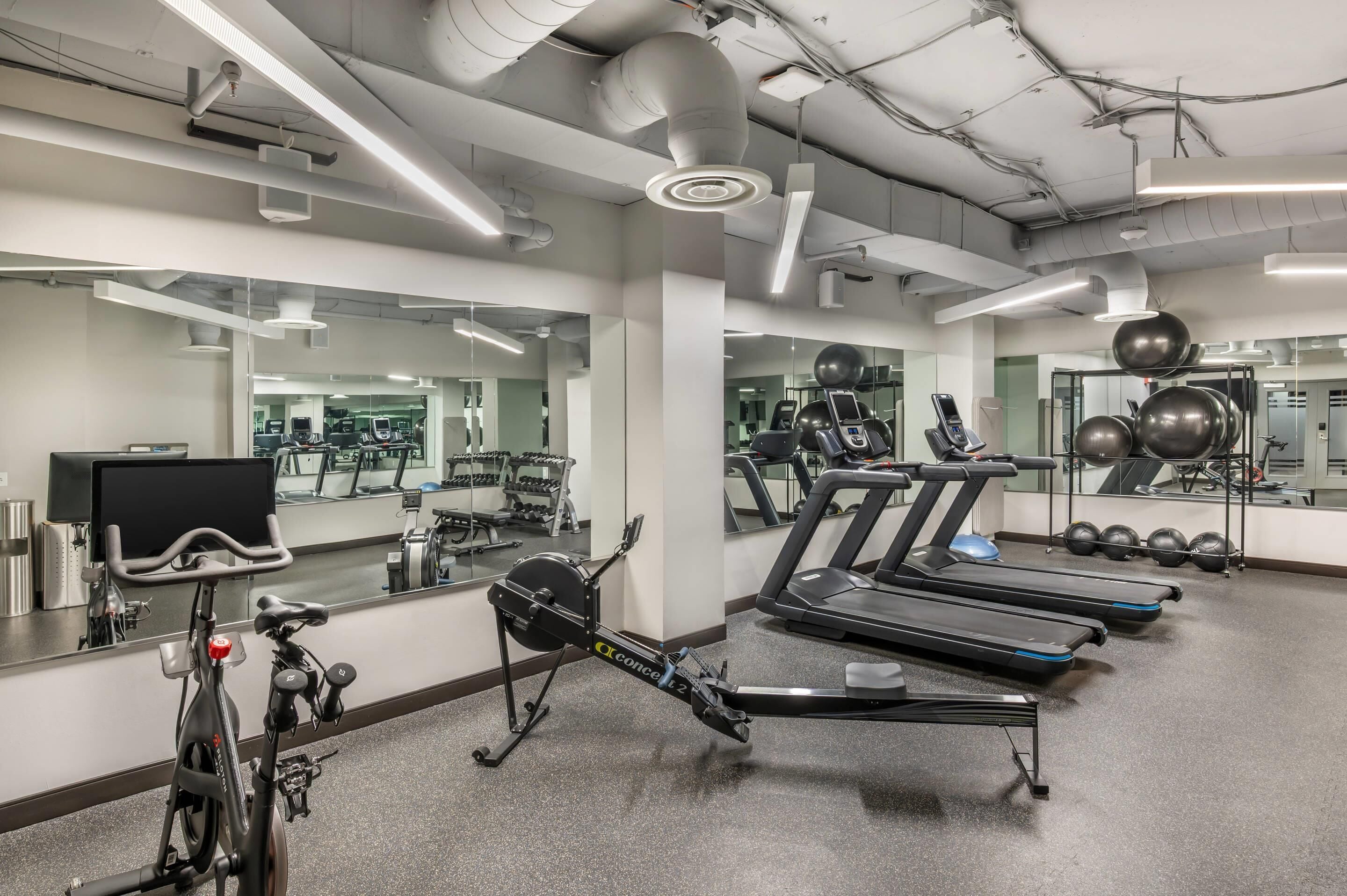 A gym with exercise equipment, mirrors, and a treadmill.
