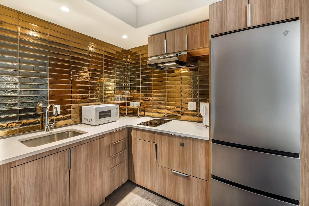 Une cuisine moderne avec des meubles en bois, un réfrigérateur en acier inoxydable, un four à micro-ondes et un évier.