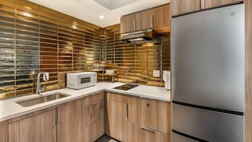 Una cocina moderna con armarios de madera, un refrigerador de acero inoxidable, un microondas y un lavamanos.